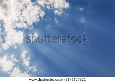 Nature background with blue sky with clouds and sun rays shine down through the haze.
