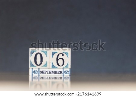 Wooden calendar dated 6 September. Daily calendar block sets for the month. Still life in the home studio with dark background and copy space.