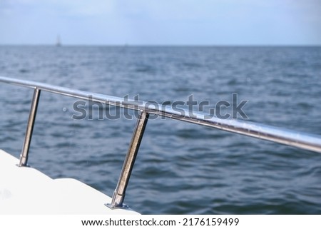 View on the water and in the foreground a boat railing in silver Royalty-Free Stock Photo #2176159499