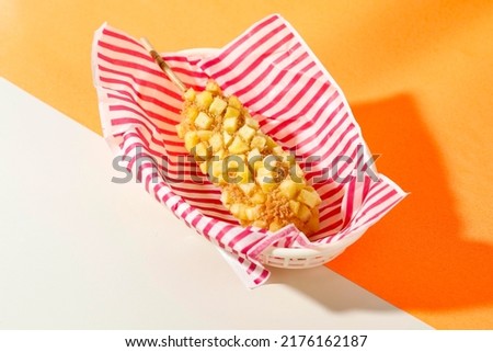 Delicious Crunchy Korean Style Chunky Potato Corn Dogs with Batter and Fried Potatoes. Isolated on Orange  Background with Copy Space for Text Royalty-Free Stock Photo #2176162187