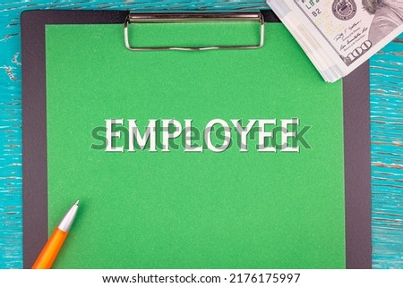 EMPLOYEE - word (text) and money a pack of dollar bills on a green background notepad, pen. Business concept: buy, sell (copy space).