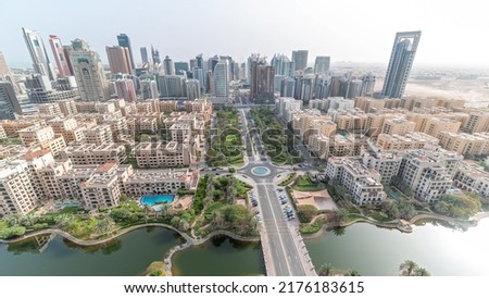 Skyscrapers in Barsha Heights district and low rise buildings in Greens district aerial timelapse. Dubai skyline look down panoramic view with palms and trees near pond Royalty-Free Stock Photo #2176183615