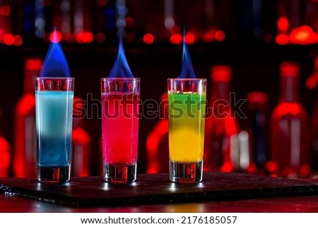 Cocktails Burning Shots and Shooters on bar counter in a restaurant, pub. Miniature mixed drinks. Alcoholic cooler beverage at nightclub on dark background.