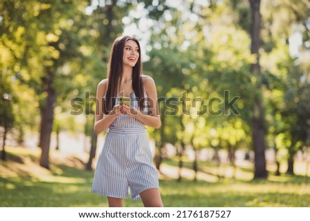 Photo of adorable good mood positive girl walk summer season surfing telephone look sideways laugh enjoy vacation outside