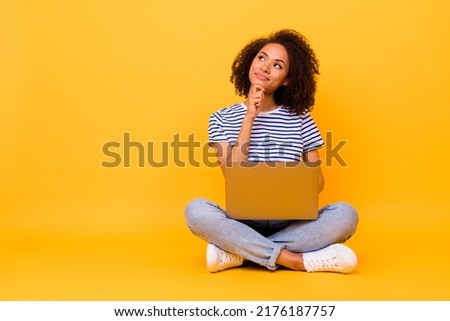 Full body portrait of minded pretty lady arm touch chin look empty space hold netbook isolated on yellow color background Royalty-Free Stock Photo #2176187757