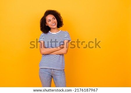Photo of pretty thoughtful girl dressed striped t-shirt arms crossed looking empty space isolated yellow color background