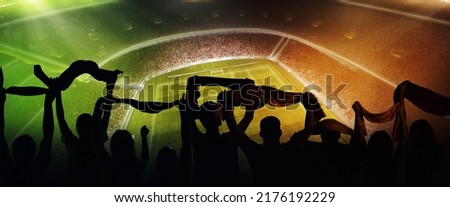 At world cup. Back view of football, soccer fans cheering their team with and scarfs at crowded stadium at evening time. Concept of sport, cup, world, team, event, competition. Green and orange Royalty-Free Stock Photo #2176192229