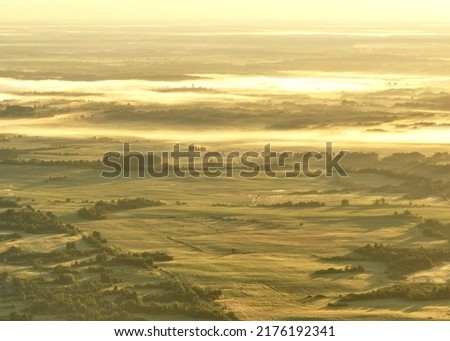 Foggy sunrise. Nature at dawn in fog, aerial view. Rural landscape with a small lake in forest. Morning mist haze. Misty landscape. Sunny foggy hills on sundown. Freshwater lakes. Idyllic landscape.