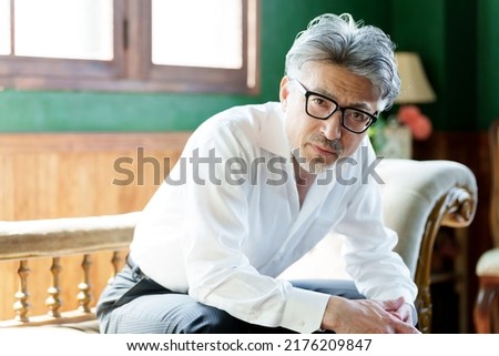 middle aged asian man with gray hair relaxing on sofa Royalty-Free Stock Photo #2176209847