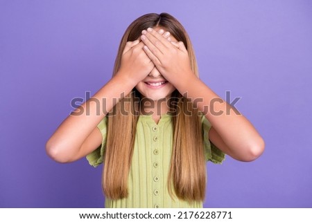 Photo of cheerful excited girl arms palms cover eyes toothy smile playing game isolated on violet color background