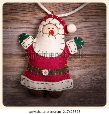 Handicraft Christmas decoration, felt Santa Claus, over old wood background.  Filtered to look like an aged instant photo.