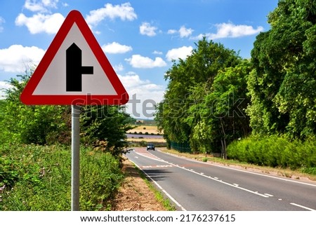 UK road sign. Side Road Ahead along a country lane. Blue cloudy sky