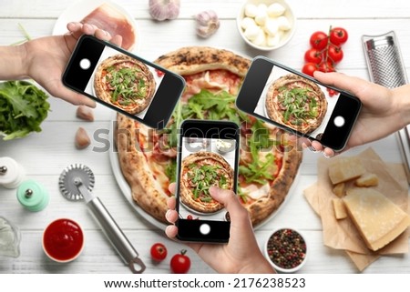 People taking pictures of tasty pizza on white wooden table, top view