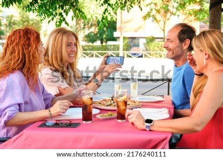 Woman showing a selfie photo she took to her group of mature friends. Pizzeria.