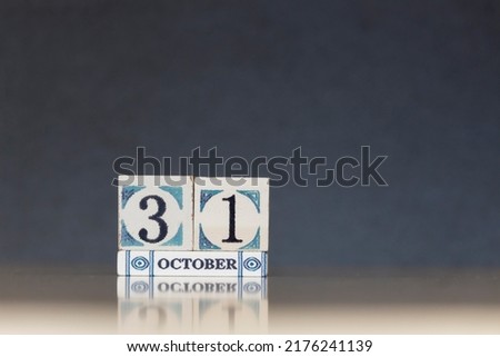 Wooden calendar dated 31 October. Daily calendar block sets for the month. Still life in the home studio with dark background and copy space.