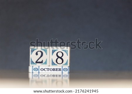 Wooden calendar dated 28 October. Daily calendar block sets for the month. Still life in the home studio with dark background and copy space.