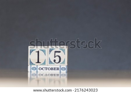 Wooden calendar dated 15 October. Daily calendar block sets for the month. Still life in the home studio with dark background and copy space.