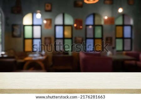 Empty wooden desk with blurry background of cafe or bistro. For present product.