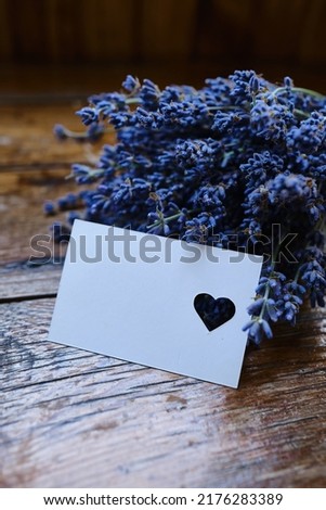 Mockup of a greeting card or card for wishes and a bouquet of lavender on a wooden background. Greeting card. Bouquet of fragrant lavender. Place for text