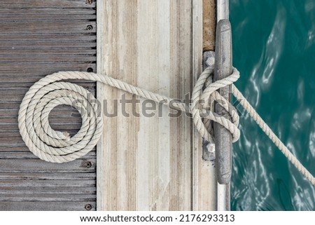 Mooring rope with a knotted end tied around a cleat Royalty-Free Stock Photo #2176293313