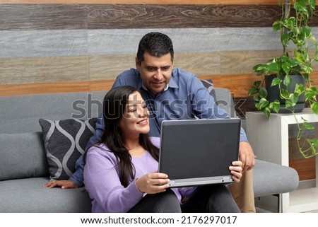 Latino adult man and woman couple use their laptop in the living room to shop online, make payments, plan trips, view photos and make video calls
 Royalty-Free Stock Photo #2176297017