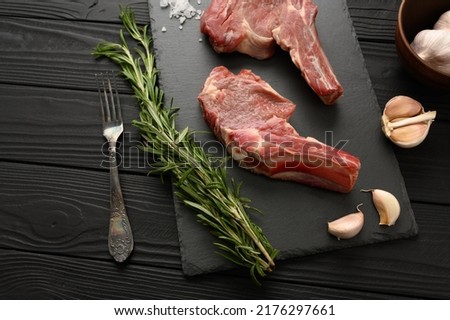 Raw cowboy steak and spices on a black wooden background. BBQ Top view. Free space for text.