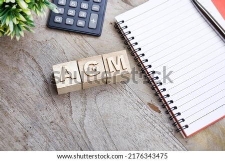 Words on AGM on the wooden blocks with a notebook, and calculator. Business and annual general meeting concept Royalty-Free Stock Photo #2176343475
