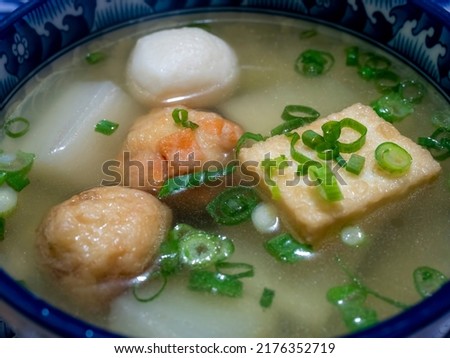 Close-up of a bowl of simple homemade Japanese Oden Soup, consisting fish cakes and fish balls, and daikon (white radish), in a light and healthy soy-flavored dashi broth. A catering concept.