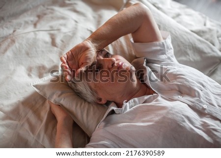Unhappy elderly woman lying in bed at home thinking pondering over life problems, mourning or yearning, upset sad senior female relax in bedroom feel unwell or stressed suffering from insomnia Royalty-Free Stock Photo #2176390589