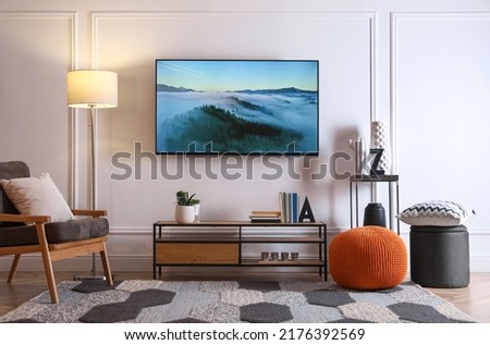 Stylish room interior with modern TV, armchair and decor Royalty-Free Stock Photo #2176392569