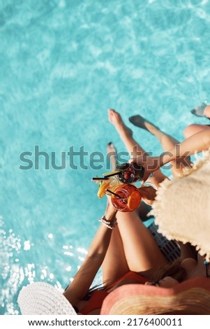 Close up of female friends having fun while toasting with cocktails on summer day at swimming pool. Copy space.  Royalty-Free Stock Photo #2176400011