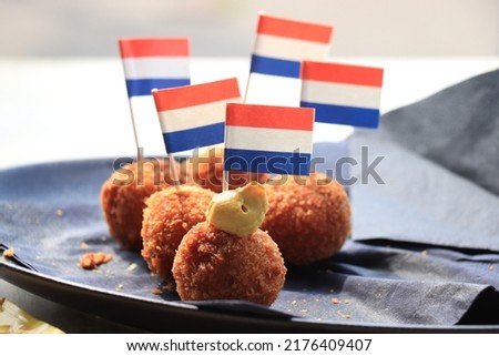 Dutch Bitterballen with mustard, warm stuffed fried meatballs, served in the Netherlands and decorated with the dutch flag Royalty-Free Stock Photo #2176409407