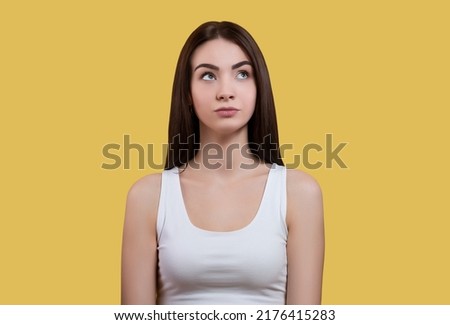 Portrait of attractive coquettish cute funny cheerful girl in white top isolated on yellow background