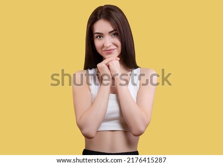 Portrait of attractive coquettish cute funny cheerful girl in white top isolated on yellow background