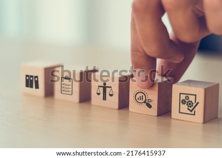 Audit business concept. Examination and evaluation of the financial statements of an organization; income statement, balance sheet, cash flow statement.  Holding wooden cubes with audit icon. Royalty-Free Stock Photo #2176415937