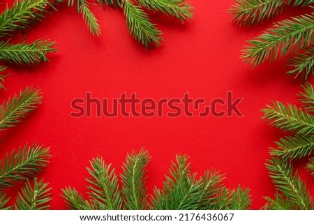 Christmas red background from green fir branches, frame, top view	