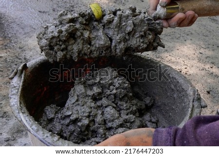 Close up shot of a worker's hands mixing cement to work on a floor. This cement mixing is done manually by hand.                    Royalty-Free Stock Photo #2176447203
