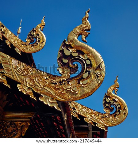 Golden carved serpent on blue sky background, Thailand