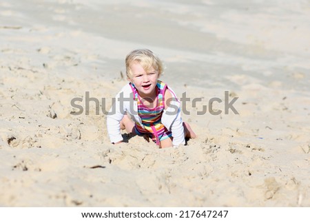 Happy little child, adorable blonde toddler girl, playing and running on the beautiful peaceful sandy beach at the sea