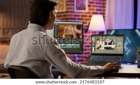 Asian videographer editing multimedia film footage on pc, using visual effects software on display. Developing video montage with color gradient, creating professional content. .