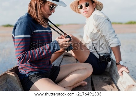 Outdoor travel concept, Asian men and women taking pictures. and see the view on a wooden boat happily.