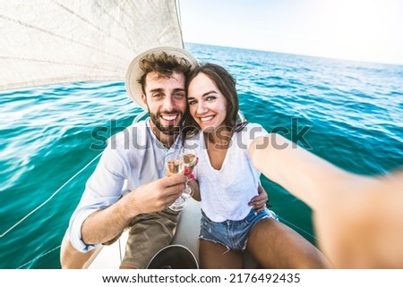 Happy couple of lovers enjoying sail boat trip experience in the ocean - Boyfriend and girlfriend taking selfie picture outside on summer vacation 