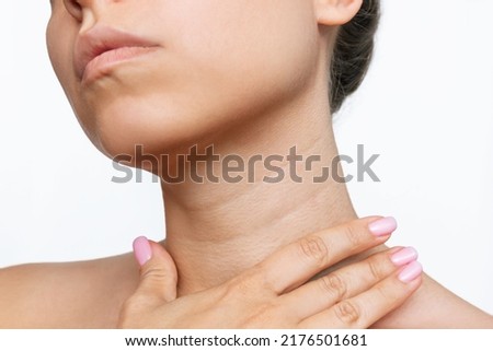 Cropped shot of a young woman touching her neck with her hand isolated on a white background. Lines on the neck. Wrinkles, age-related changes, rings of Venus, goosebumps