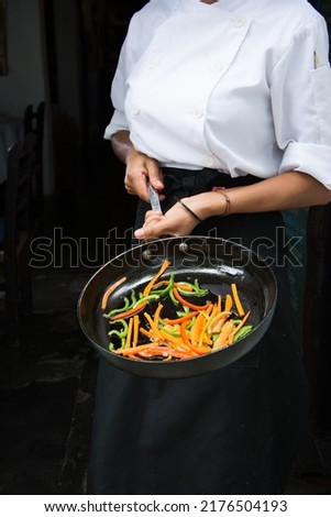 Female cook holding pan with vegetables
