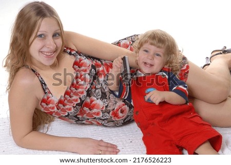 Beautiful young mother in a red-black dress with her little son in a red overalls