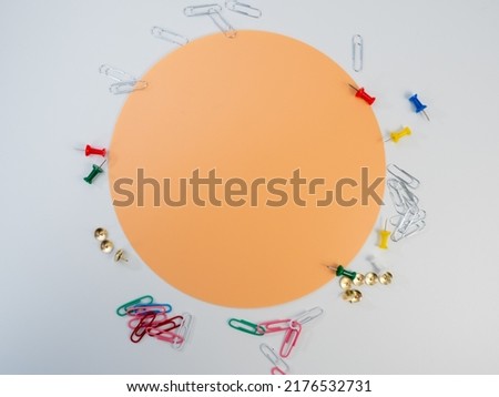 Set of colored paper clips and thumbtacks. Buttons and paper clips around the orange circle.