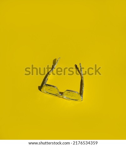 Sunglasses wrapped in aluminum foil on a yellow background. Summer idea of ​​maximum sun protection.