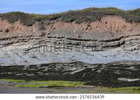 Multiple layers of geological strata on cliff face on north of Annstead Beach between Seahouses and Beadnell, Northumberland, England Royalty-Free Stock Photo #2176536439