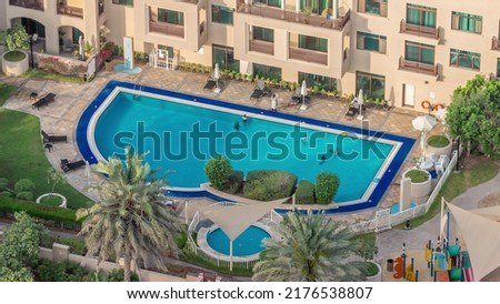 Swimming pool with blue water viewed from above timelapse, Aerial top view in Greens district. People swimming and relaxing on a chaise longue. Dubai, UAE