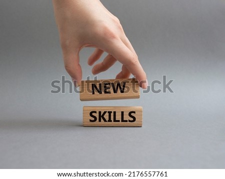 New skills symbol. Wooden blocks with words New skills. Beautiful grey background. Businessman hand. Business and New skills concept. Copy space.